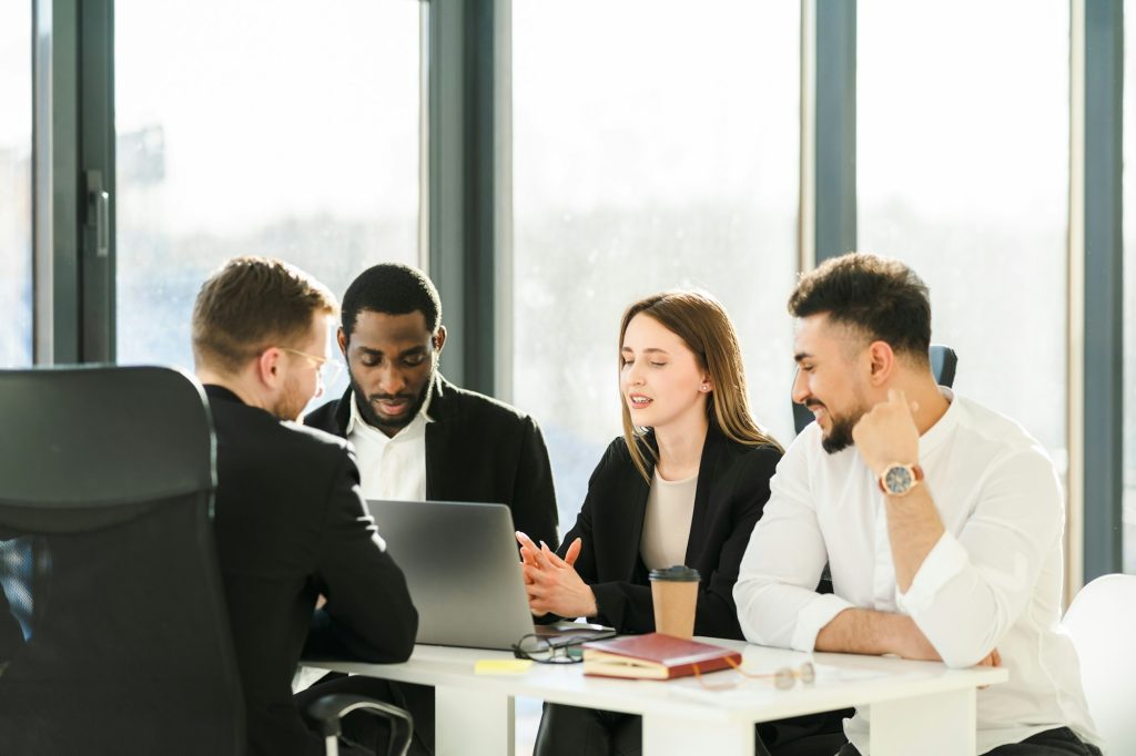Young office workers hold business negotiations in the office sitting in front of a laptop